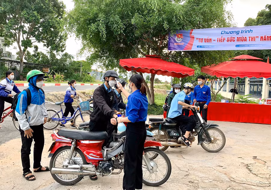 Các tình nguyện viên đo thân nhiệt. sát khuẩn tay cho các thí sinh tại điểm thi Trường THPT Lý Thường Kiệt. Ảnh: Vũ Chi