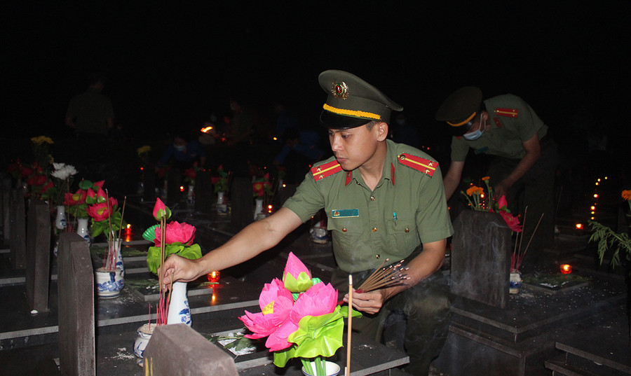 Trung uý Ngô Viết Hùng-đoàn viên Đoàn Thanh niên Công an tỉnh thắp hương tại phần mộ các liệt sĩ. Ảnh: Phan Lài