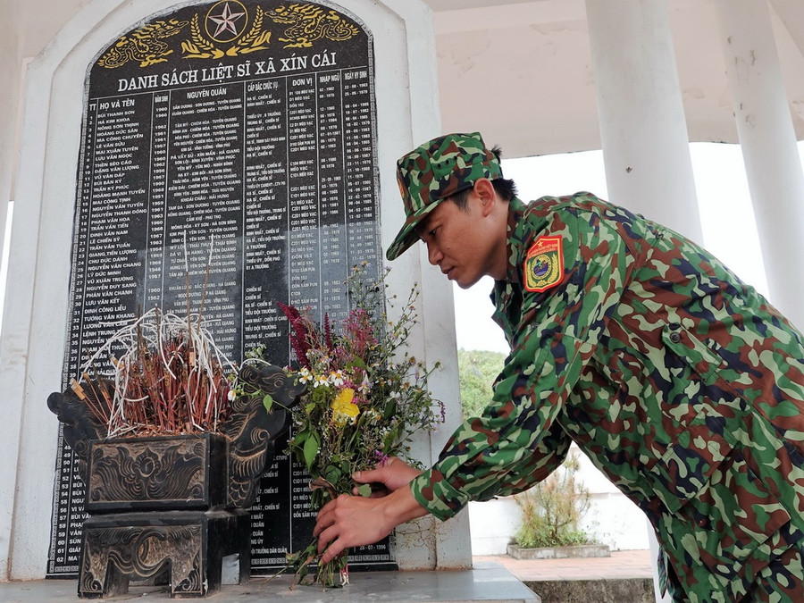 Thiếu tá Nguyễn Văn Chủng (Chính trị viên phó đồn BP Xín Cái) đặt hoa rừng trước bia ghi danh các liệt sĩ đã hy sinh trên địa bàn xã Xín Cái (H.Mèo Vạc, Hà Giang). Ảnh: Mai Thanh Hải