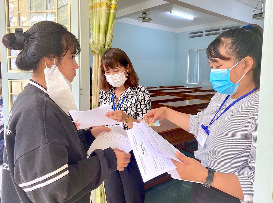Giám thị kiểm tra, đối chiếu thông tin của thí sinh trước khi vào phòng thi. Ảnh: Mộc Trà