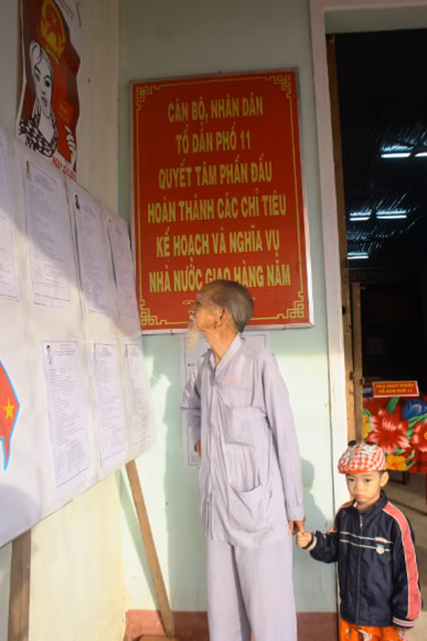 Cử tri Đặng Xuân Sinh (86 tuổi)-tổ 11, phường Hoa Lư (TP. Pleiku) xem lại tiểu sử các ứng cử viên trước khi bỏ phiếu. Ảnh: Nguyễn Dung