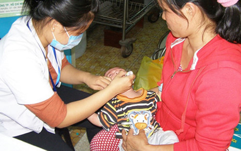 Một trẻ đang được nhân viên y tế cho uống vắc xin bại liệt. (Ảnh: PLO)