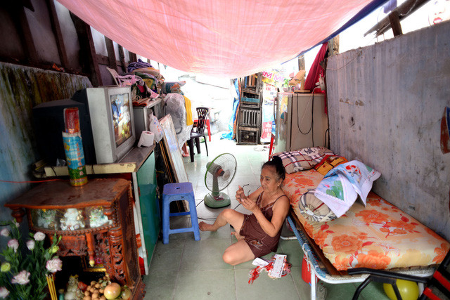 Bà Gái (63 tuổi) với ít đồ đạc bên trong căn nhà chỉ còn hai bức tường chắn, phía trên là tấm bạt che mưa nắng. Gia đình bà nằm trong diện giải tỏa, nên bà ở lại canh đồ đạc chờ các con thuê được phòng sẽ chuyển qua.