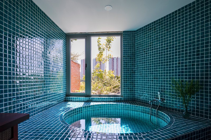 Bồn tắm hình tròn đặt trong một phòng tắm ốp đá màu xanh, trông giống như spa. Bồn tắm hình tròn đặt trong một phòng tắm ốp đá màu xanh, trông giống như spa.