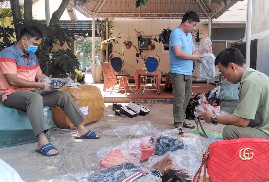 Lực lượng Quản lý Thị trường kiểm đếm số lượng túi xách giả mạo nhãn hiệu tại một cơ sở kinh doanh trực tuyến. Ảnh: V.T