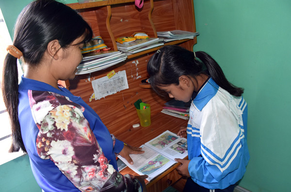 Chị Đinh Thị Tơn hướng dẫn con gái học bài. Ảnh: T.B