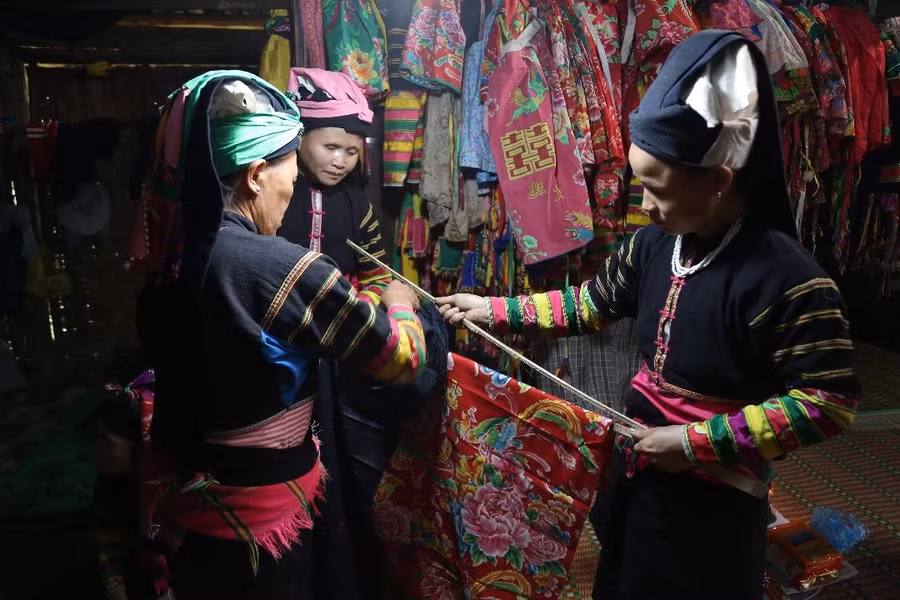 Người dân chuẩn bị vải để treo lên cây nêu trước sân nhà làm lễ.