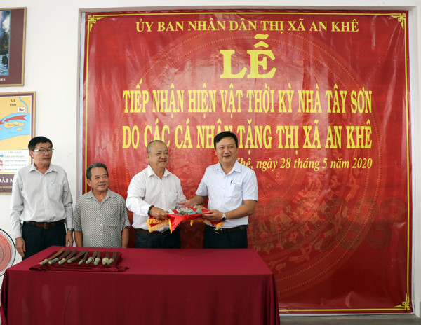 Ông Lâm Dũ Xênh (thứ 3 bên trái_ huyện Bình Sơn, tỉnh Quảng Ngãi) trao tặng 99 đồng tiền và 8 cái lục lạc đồng thời kỳ nhà Tây Sơn cho thị xã An Khê. Ảnh: N.M