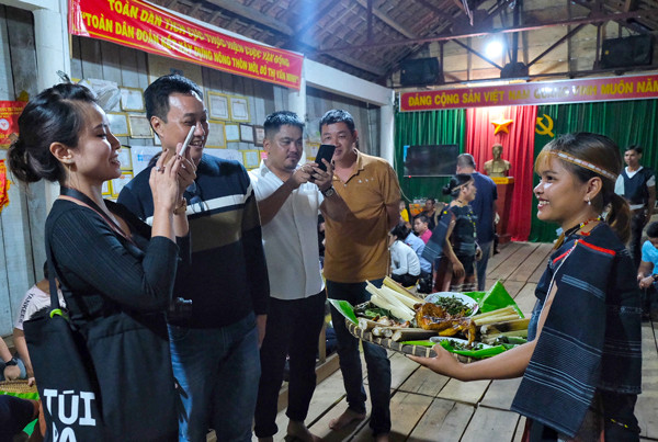 Du khách hào hứng trải nghiệm ẩm thực bản địa tại làng Mơ Hra. Ảnh: M.C