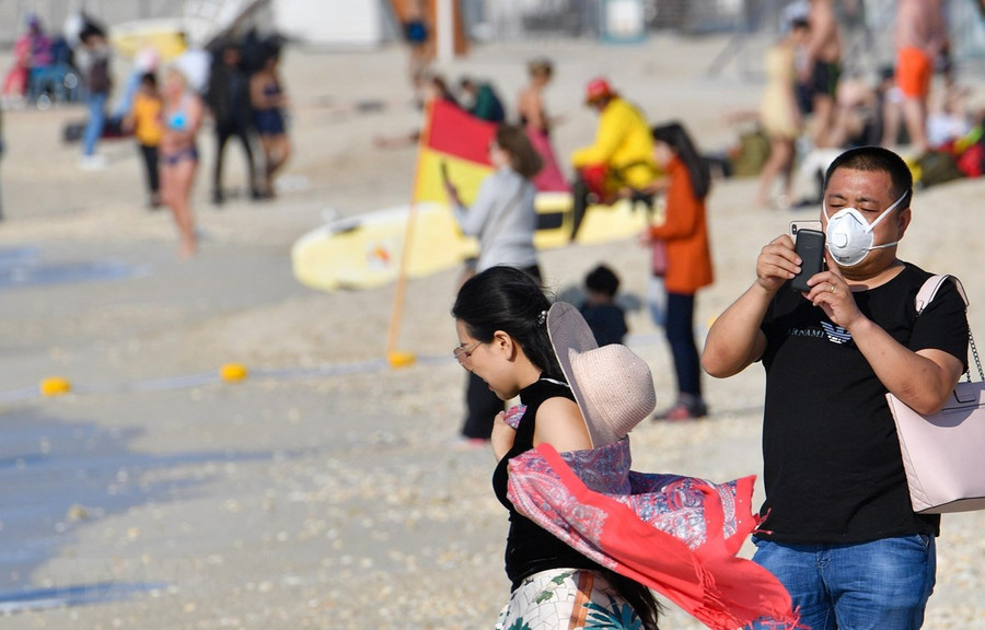 Khách du lịch đeo khẩu trang vui chơi trên bãi biển Dubai, UAE. (Ảnh: AFP/TTXVN)