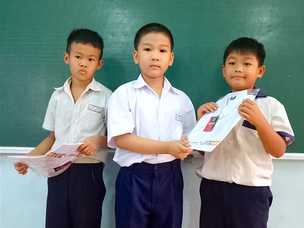 Bé Ngô Hải Long lớp 2/1, Trường Tiểu học Lương Thạnh (giữa) tặng áo mới cho hai bạn có hoàn cảnh khó khăn trong lớp từ chính số tiền tiết kiệm của mình. Ảnh: M.T