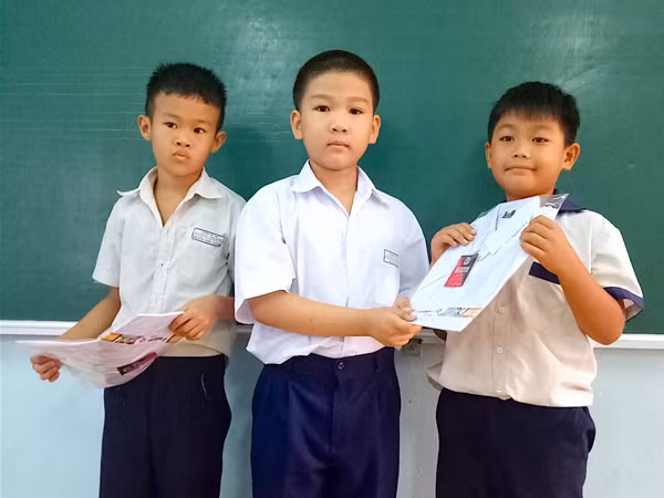 Bé Ngô Hải Long lớp 2/1, Trường Tiểu học Lương Thạnh (giữa) tặng áo mới cho hai bạn có hoàn cảnh khó khăn trong lớp từ chính số tiền tiết kiệm của mình. Ảnh: M.T