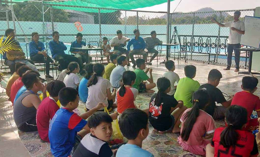 Giáo viên hướng dẫn kỹ năng khởi động cho cán bộ Đoàn và thiếu nhi trước khi xuống bể bơi. Ảnh: Phan Lài 