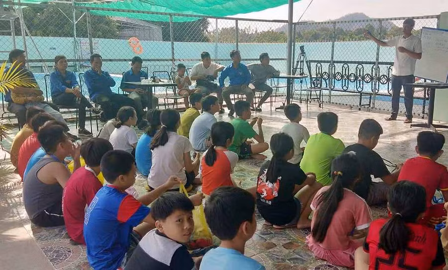 Giáo viên hướng dẫn kỹ năng khởi động cho cán bộ Đoàn và thiếu nhi trước khi xuống bể bơi. Ảnh: Phan Lài 