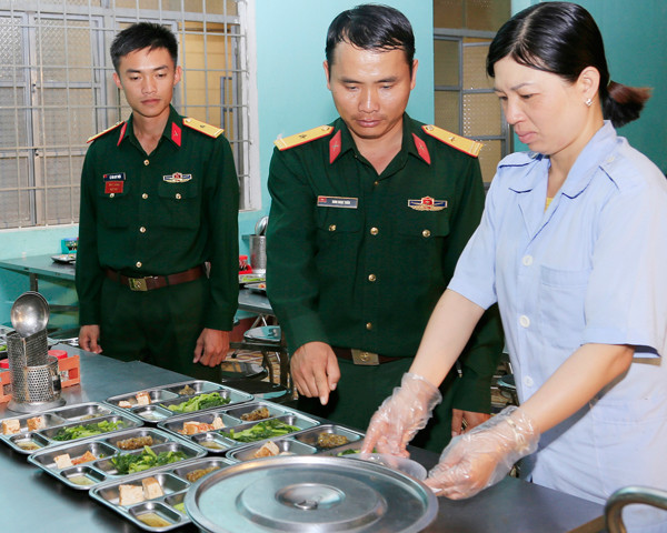 Thiếu tá Đinh Ngọc Tuân (giữa) kiểm tra việc chuẩn bị bữa ăn cho bộ đội. Ảnh: V.D.H