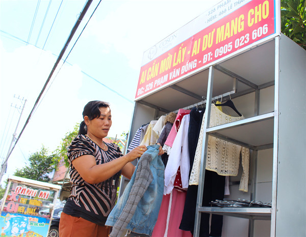 Bà Cao Thị Mỹ Dung cẩn thận treo quần áo vào tủ để mọi người dễ chọn lựa. Ảnh: M.T