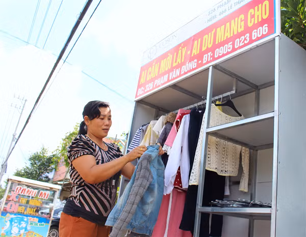 Bà Cao Thị Mỹ Dung cẩn thận treo quần áo vào tủ để mọi người dễ chọn lựa. Ảnh: M.T