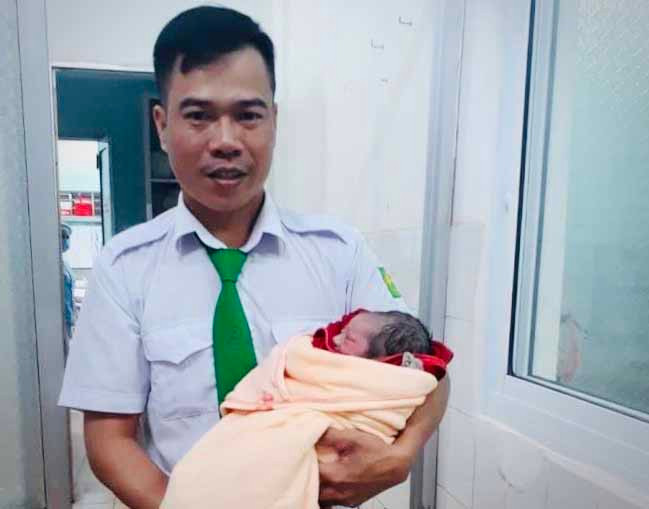 “Bà đỡ” bất đắc dĩ-tài xế Nguyễn Quang Điệp bế trên tay em bé do chính anh và bố đứa bé đỡ đẻ thành công trên xe taxi. Ảnh: Hải Lê
