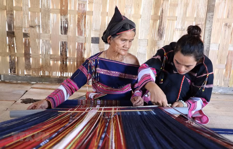 Chị Hồ Thị Viên (bên phải) cùng một nghệ nhân lớn tuổi hoàn thành sản phẩm thổ cẩm tại làng dệt Pơ Nang, xã Tú An, thị xã An Khê, tỉnh Gia Lai. (Ảnh: Hồng Điệp/TTXVN)