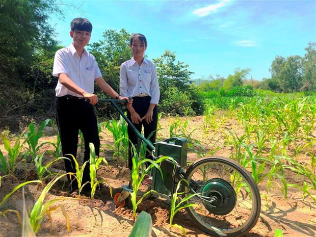 Em Phạm Thị Hoài Phương và Lê Tuấn Kiệt với máy cày điện để làm cỏ, bón phân. (Ảnh: Nguyên Linh/TTXVN)