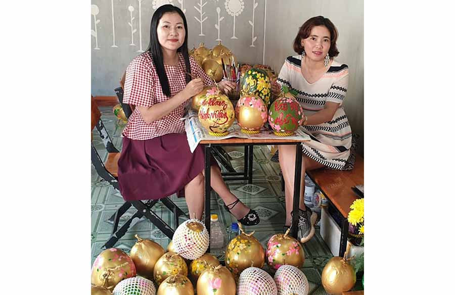  Chị Phan Kim Thanh (bìa trái) và chị Lê Thị Kim Thúy đang vẽ thư pháp trên quả dừa. Ảnh: V.M.H