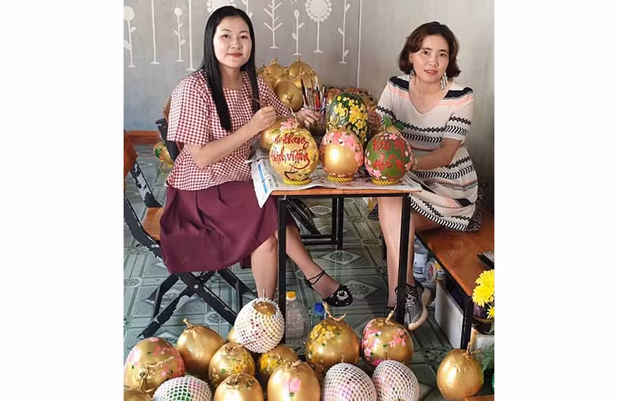  Chị Phan Kim Thanh (bìa trái) và chị Lê Thị Kim Thúy đang vẽ thư pháp trên quả dừa. Ảnh: V.M.H