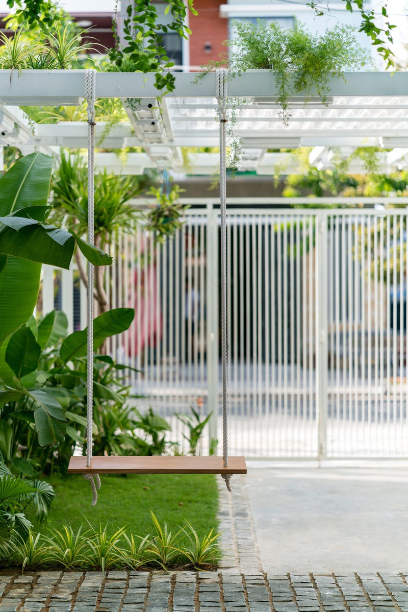 Một chiếc xích đu đặt trước nhà, cạnh bên thảm cỏ xanh mướt.