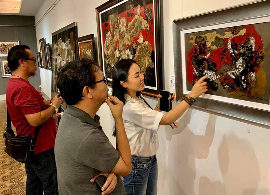 Trần Ngọc Linh giới thiệu cho khách tham quan về tranh sơn mài tại triển lãm cá nhân (Ảnh nhân vật cung cấp).