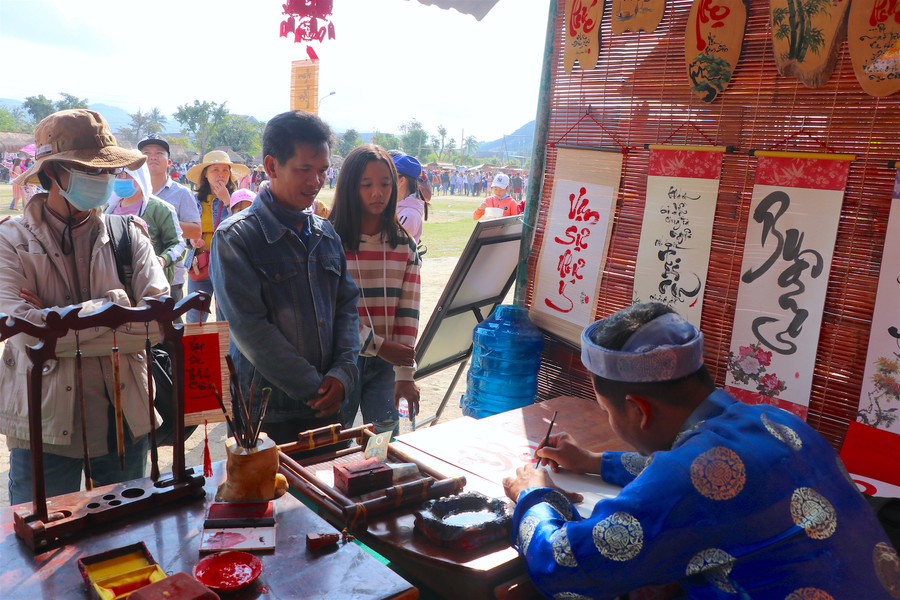 Du khách xin chữ ông đồ đầu năm tại hội Cầu Huê. Ảnh: Ngọc Minh