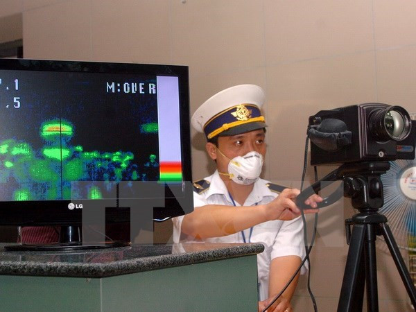 Kiểm tra thân nhiệt hành khách ở cửa khẩu Nội Bài. (Ảnh: TTXVN)