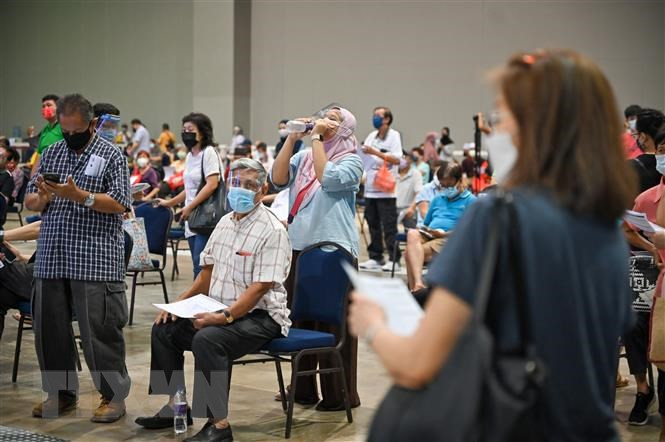  Người dân xếp hàng chờ tiêm vaccine ngừa COVID-19 ở Kuala Lumpur, Malaysia. (Ảnh: AFP/TTXVN)