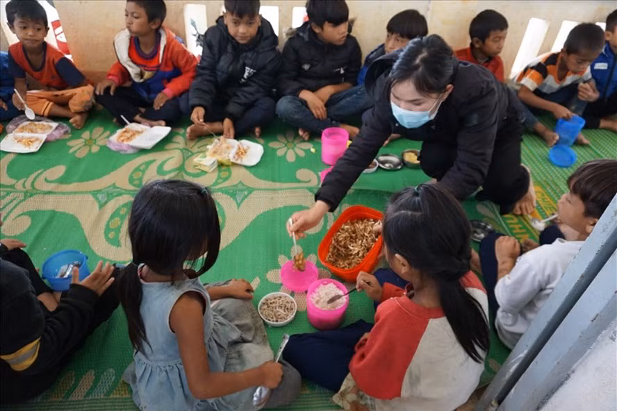 Cô giáo thêm món cá khô cho các em học sinh ở điểm trường Kon Du. Ảnh T.T