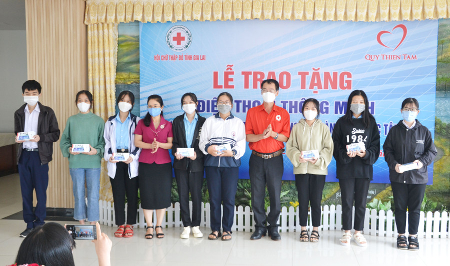  Từ phải qua trái là ông Dương Đình Diện (người thứ 4)-Chủ tịch Hội Chữ thập đỏ tỉnh và bà Bùi Khoa Nghi (người thứ 7)-Phó Giám đốc Sở Giáo dục và Đào tạo tỉnh trao tặng điện thoại cho học sinh THPT gặp khó khăn. Ảnh: Hoàng Minh.
