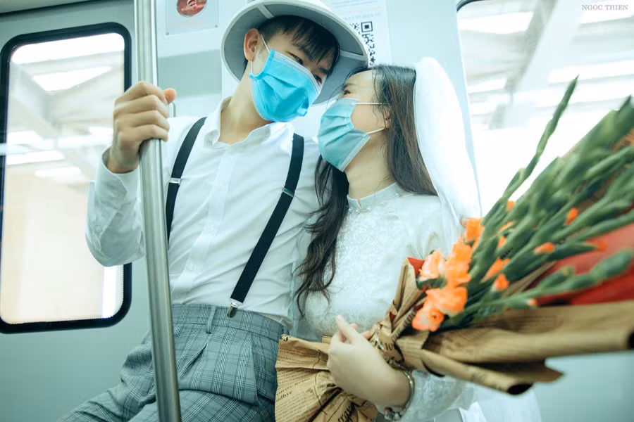 Cặp đôi trẻ đeo khẩu trang khi lên tàu. Ảnh: Vũ Ngọc Thiện