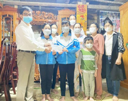 Thầy Phan Đình Toàn (bìa trái)-Hiệu trưởng Trường THCS Nguyễn Bỉnh Khiêm trao số tiền hỗ trợ 2 triệu đồng do Liên Đội nhà trường quyên góp, vận động cho gia đình 2 em Dung, Xuân. Ảnh: Phương Duyên