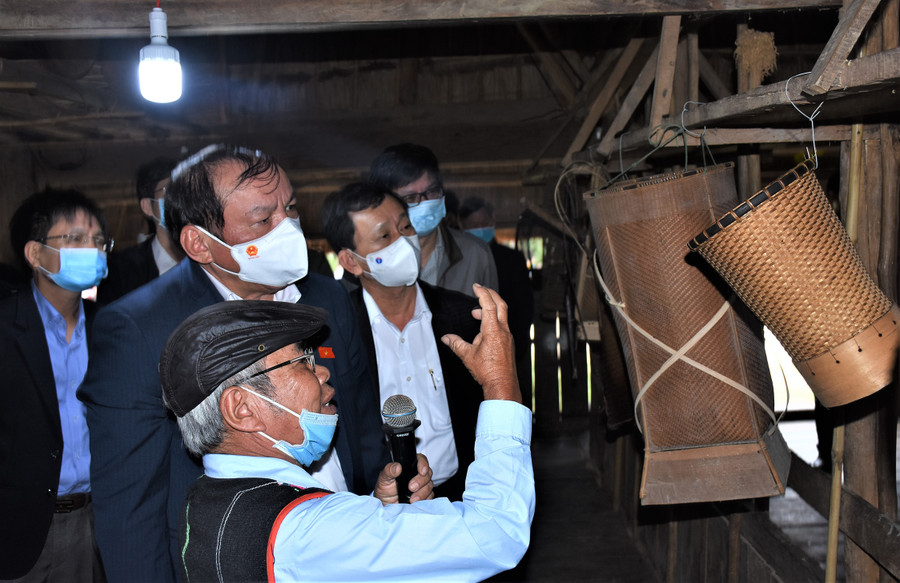 Già A Ring Đeng ở làng Kon Brắp Ju giới thiệu với các đồng chí lãnh đạo về những vật dụng ý nghĩa trong nhà rông. Ảnh: VP