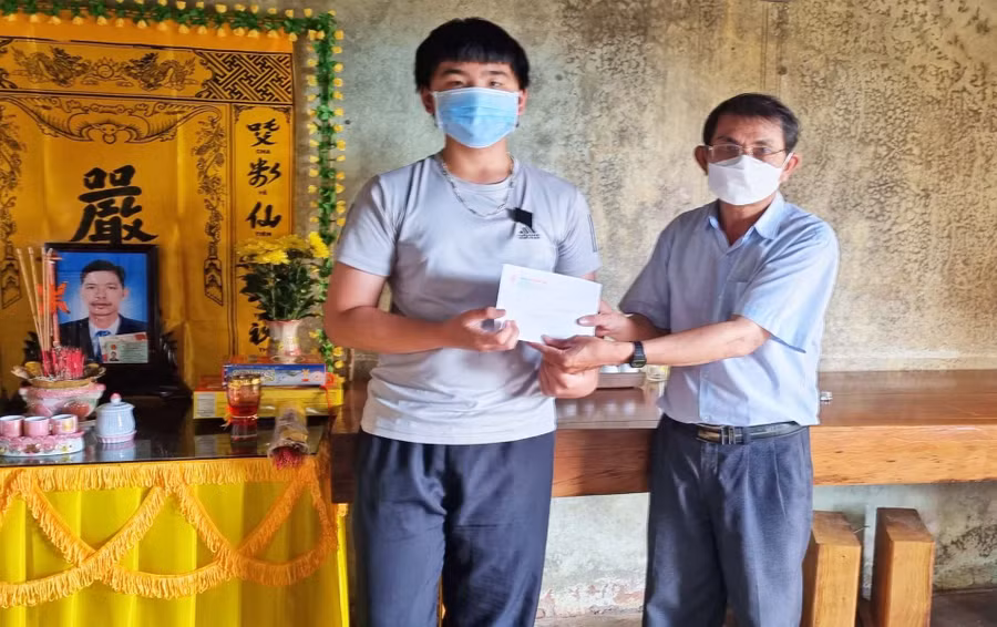Cháu Nguyễn Quốc Hậu (con trai anh Hùng) nhận số tiền do bạn đọc và Báo Gia Lai hỗ trợ. Ảnh: Lệ Hằng