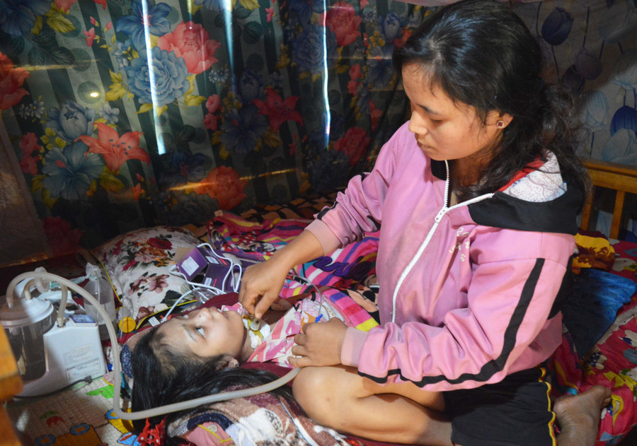 Chị Vên đang hút đờm cho con gái Siu Phen. Ảnh: Phương Dung