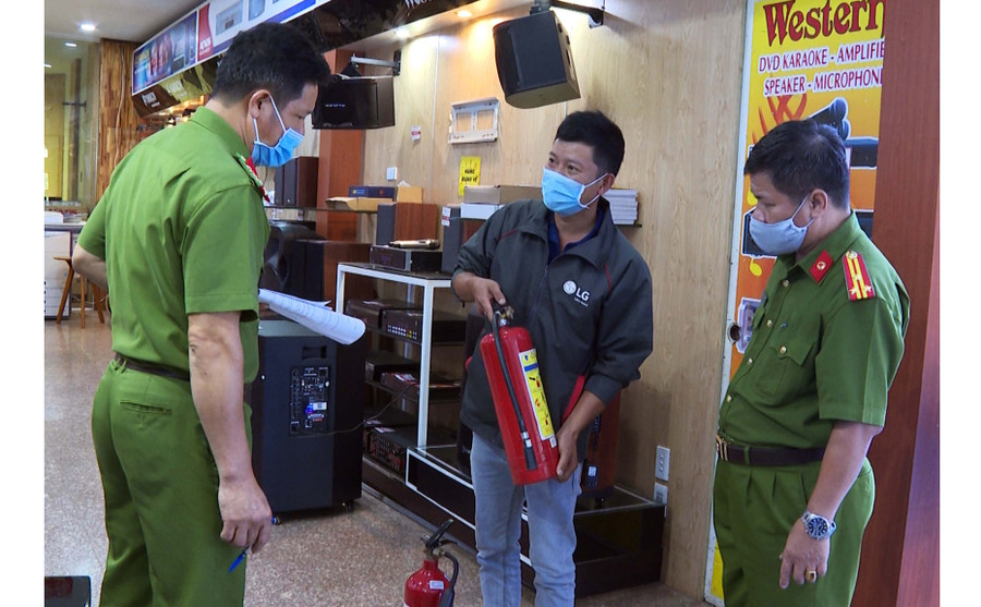 Lực lượng Công an hướng dẫn chủ nhà ở kết hợp sản xuất kinh doanh sử dụng thiết bị chữa cháy. Ảnh: Lê Ánh
