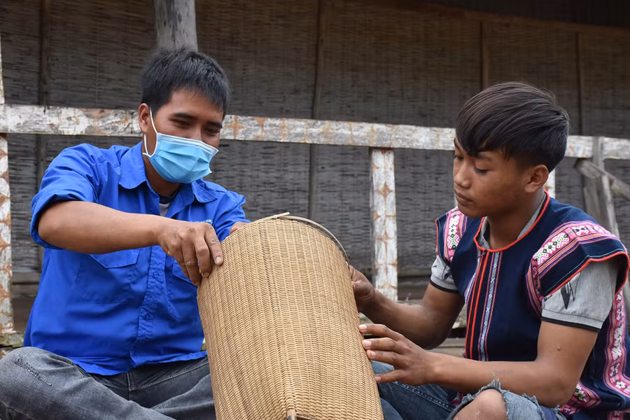  Anh Đinh Văn Hlinh (bìa trái) hướng dẫn thanh niên học nghề đan lát. Ảnh: Mai Ka