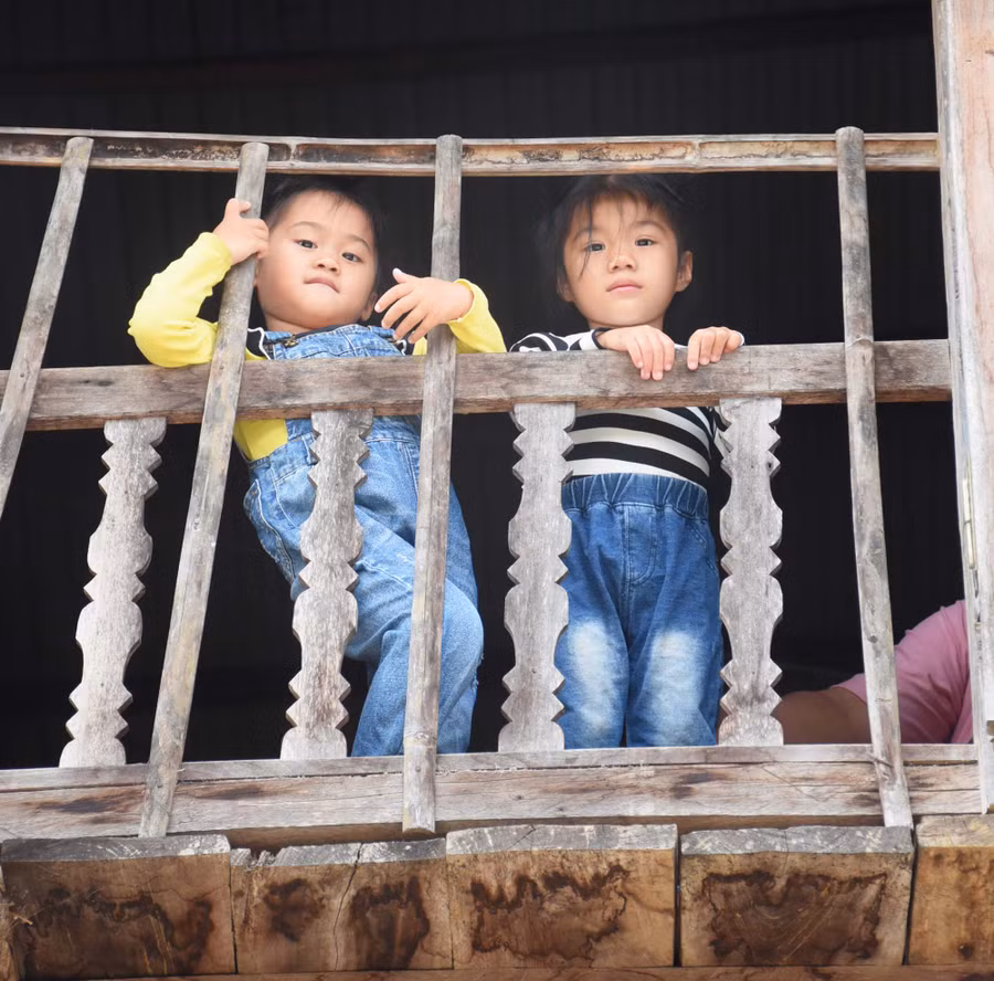 2 bé Bảo An, Linh Nhi tạm biệt khách từ cửa sổ nhà sàn. Ảnh: Phương Duyên