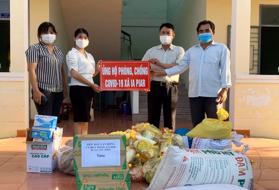 Đại diện Tiểu ban Vận động và huy động xã hội huyện Phú Thiện trao quà cho lãnh đạo UBND xã Ia Piar để hỗ trợ người dân khu vực phong tỏa và lực lượng chốt kiểm soát dịch. Ảnh: Vũ Chi