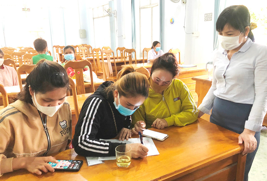 Cán bộ Trung tâm dịch vụ việc làm tỉnh hướng dẫn lao động xã Chư Gu, huyện Krông Pa viết phiếu đăng ký quay lại tỉnh Bình Dương làm việc. Ảnh: Đinh Yến