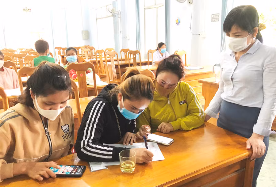 Cán bộ Trung tâm dịch vụ việc làm tỉnh hướng dẫn lao động xã Chư Gu, huyện Krông Pa viết phiếu đăng ký quay lại tỉnh Bình Dương làm việc. Ảnh: Đinh Yến