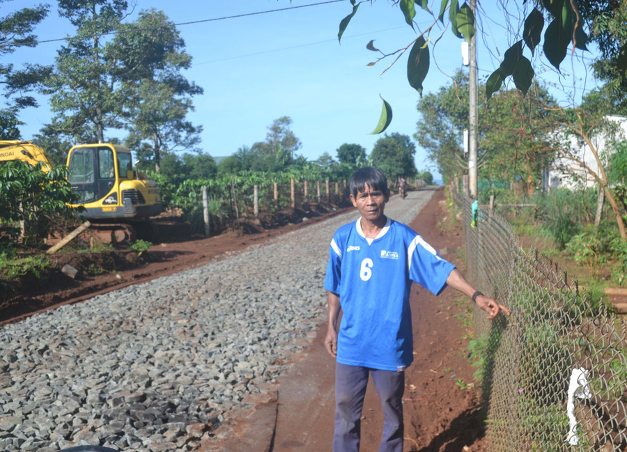 Ông Rơ Châm Mook (làng Tốt) chỉnh sửa lại hàng rào của gia đình sau khi hiến đất làm đường giao thông. Ảnh: Hoàng Cư