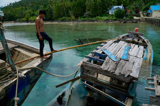 Một ngư dân VN đứng nhìn chiếc tàu cá bị đánh đắm trên đảo Tiga Một ngư dân VN đứng nhìn chiếc tàu cá bị đánh đắm trên đảo Tiga