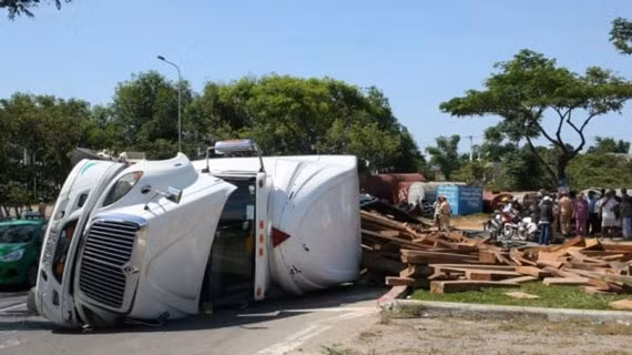 Hiện trường xe đầu kéo chở gỗ bị lật ngang khiến QL1A bị ách tắc.