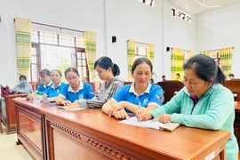 Cán bộ Tổ Tiết kiệm và Vay vốn Chi hội Phụ nữ thuộc nhiều thôn (xã Vạn Đức) hỗ trợ người dân làm thủ tục vay vốn, trả tiền lãi. Ảnh: Duy Đăng