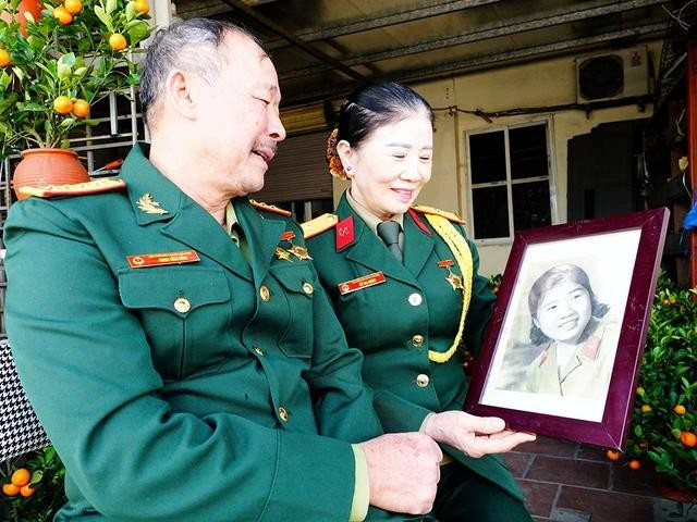 Ông Bản và bà Châm bên tấm hình bà Châm hồi mới nhập ngũ Ông Bản và bà Châm bên tấm hình bà Châm hồi mới nhập ngũ