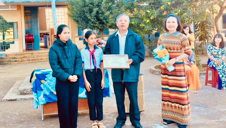 Ông Đinh Xuân Thao-Chủ tịch Hội khuyến học huyện Ia Grai tặng giấy chứng nhận danh hiệu &quot;Học không bao giờ cùng&quot; và số tiền 3 triệu đồng cho em Puih H&apos; Pưn-Trường Tiểu học Lý Tự Trọng, xã Ia Chía, huyện Ia Grai. Ảnh: Xuân Thao